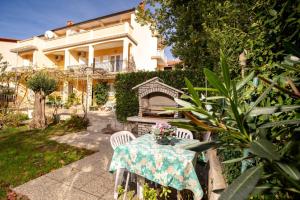 a table with a vase of flowers on it in a garden at Apartments Rajska Plaza (129) in Lopar