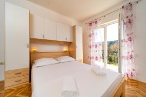 a bedroom with a white bed and a window at Apartments Rajska Plaza (129) in Lopar