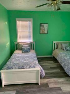a green bedroom with two beds and a window at Remodeled House Minutes to Falls Attractions in Niagara Falls
