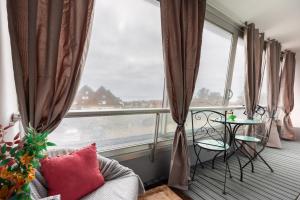 d'un balcon avec un canapé, une table et des fenêtres. dans l'établissement Le Pavillon - Appartement à 30 m de la plage, à Courseulles-sur-Mer
