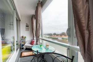 un petit balcon avec une table, des chaises et une fenêtre dans l'établissement Le Pavillon - Appartement à 30 m de la plage, à Courseulles-sur-Mer 7 autres photos