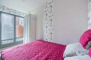 - une chambre avec un lit rose et une fenêtre dans l'établissement Le Pavillon - Appartement à 30 m de la plage, à Courseulles-sur-Mer