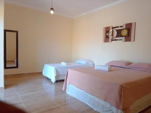 a hotel room with two beds and a mirror at Pousada Nobre in São Miguel do Gostoso