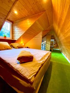 Cama grande en habitación con techo de madera en Cilensis Spa, en Sulistrowiczki
