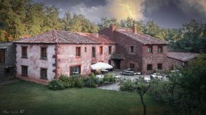 a large brick house with a garden in front of it at Molino De La Ferrería in Villacorta