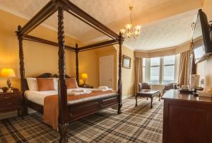 a bedroom with a four poster bed and a chair at SGE Esplanade Hotel in Dunoon