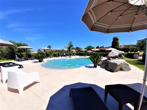 a swimming pool with chairs and an umbrella at Case Vacanze Pietragrande in Capo Vaticano