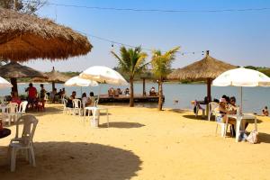 a group of people sitting on a beach with umbrellas at Hotel Marina Do Lago in Santa Cruz da Conceição