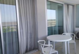 una mesa y sillas blancas en una habitación con ventana en Dpto de 1 dormitorio, 402 Dos Orillas, Colonia, en Colonia del Sacramento