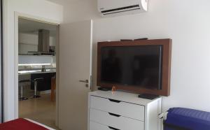 TV de pantalla plana en la parte superior de una cómoda blanca en Dpto de 1 dormitorio, 402 Dos Orillas, Colonia, en Colonia del Sacramento