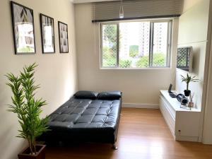 a living room with a black couch and a window at 205- Apartamento 1 quarto suite, Encantador, amplo e decorado, mobiliario moderno, cozinha completa com utensílios , Excelente vista da cidade e localização privelegiada no bairro Bigorrilho , in Curitiba