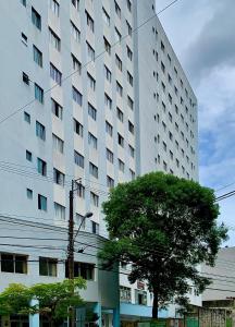 a large white building with a tree in front of it at 205- Apartamento 1 quarto suite, Encantador, amplo e decorado, mobiliario moderno, cozinha completa com utensílios , Excelente vista da cidade e localização privelegiada no bairro Bigorrilho , in Curitiba
