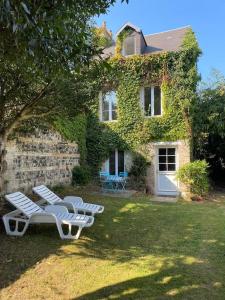 two white lounge chairs in front of a house at La Closerie un écrin de verdure à 500m de la plage in Sainte-Adresse