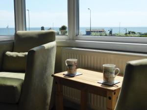zwei Kaffeetassen auf einem Tisch vor einem Fenster in der Unterkunft Bay Court in Bridlington