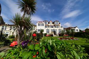 duży biały dom z palmą i kwiatami w obiekcie SGE Esplanade Hotel w mieście Dunoon