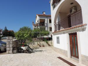 a white building with a balcony and a patio at Apartmani Antica in Cres