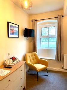 une chaise jaune dans une chambre avec un bureau et une fenêtre dans l'établissement The Green at Burnsall, à Skipton