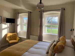 a bedroom with a bed and a chair and windows at The Green at Burnsall in Skipton