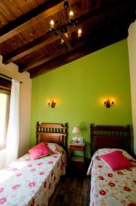 1 dormitorio con 2 camas y pared verde en Apartamentos ECOviella, en Coviella