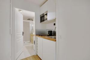 eine Küche mit weißen Schränken und einem Waschbecken in der Unterkunft Buttes Chaumont - Sunny 2P apartment in Paris