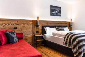 - une chambre avec deux lits et un canapé rouge dans l'établissement Apartments Rainer - Val Gardena, à Ortisei