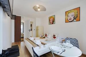 ein Wohnzimmer mit einem weißen Tisch und einem Bett in der Unterkunft Buttes Chaumont - Sunny 2P apartment in Paris