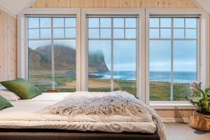 a bed sitting in front of a window with a view of the ocean at Unstad Arctic Surf in Unnstad