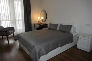 ein Schlafzimmer mit einem Bett mit einem Spiegel und einem Stuhl in der Unterkunft Kostjukowski Apartments Forum in Lwiw