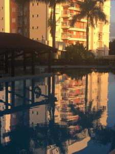 una piscina de agua con palmeras y un edificio en Apartamento em Home Club, en Penha