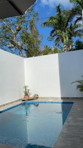a swimming pool next to a white wall at Closetoairport in Cancún
