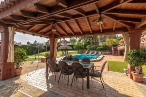 a patio with a table and chairs and a pool at Villa Olivar - 5 BDR Dream Pool/Jacuzzi/Golf/BBQ in Torremolinos