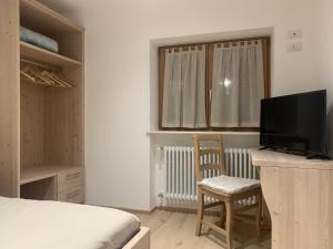 Schlafzimmer mit einem Bett und einem Schreibtisch mit einem TV in der Unterkunft La locanda di Geppetto in Bedollo