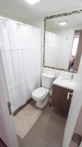 une salle de bain avec toilettes, lavabo et miroir dans l'établissement Departamento frente al mar Iquique, à Iquique