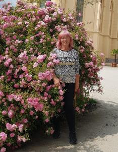 ヴァルチツェにあるUbytování nad sklípkemのピンクのバラの茂みの前に立つ女