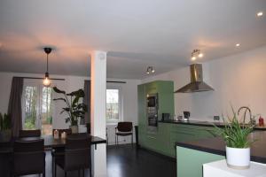 une cuisine avec des armoires vertes, une table et des chaises dans l'établissement Huis te Moerbeke-Waas, à Moerbeke