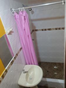 baño con cortina de ducha rosa y lavamanos en Hostal refugio's, en Ica
