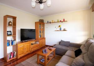 sala de estar con sofá y TV de pantalla plana en Villa Miguel, en Arnuero