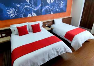 two beds in a hotel room with red and white sheets at Novo Hotel in Caracas