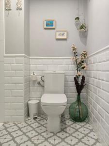een badkamer met een toilet en een vaas met bloemen bij Apartamento La Judería de San Clemente in Sevilla