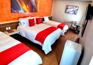 a hotel room with two beds with red and white sheets at Novo Hotel in Caracas