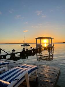 a sunset over the water with a dock and a boat at Hotel Aldea 19 Bacalar in Bacalar