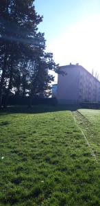 un campo de césped verde con un edificio en el fondo en LA BELLE ESCALE, en Belfort