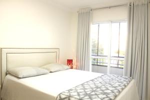 biała sypialnia z łóżkiem i oknem w obiekcie APTO completo para sua família! w mieście Cascavel
