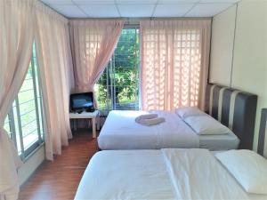 two beds in a hotel room with a window at Hasina Resort @Sedili in Kampong Bukit Lintang