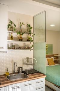 een keuken met een wastafel en een slaapkamer met een bed bij Olive Lemon Biophilic House & Lush Forest Garden in Vamos