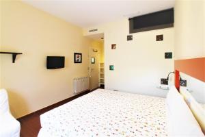 - une chambre avec un lit et une télévision murale dans l'établissement Hostal Arco Iris, à Madrid