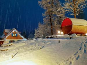 einen schneebedeckten Hof mit einem Gebäude und einem Fass in der Unterkunft Kolorowe Karkonosze in Preseka
