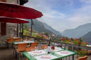 un restaurant avec des tables et un parasol rouge dans l'établissement BnB "A la Crus", à Crana