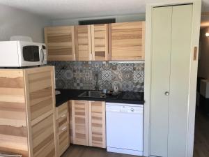 a kitchen with wooden cabinets and a white microwave at Appt rénové Saint-Lary-Soulan village avec jardin in Saint-Lary-Soulan