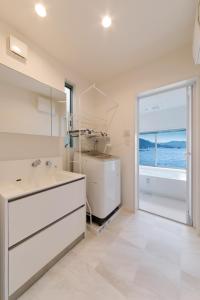 baño blanco con lavabo y ventana grande en SEASIDE TERRACE SUN - Vacation STAY 12430 en Numazu